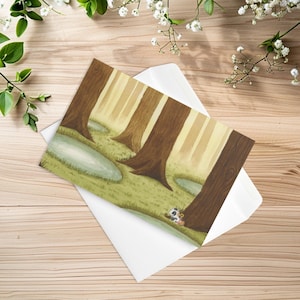 May include: A rectangular greeting card featuring a printed illustration of a forest scene with tall brown tree trunks, patches of green grass, and light blue water pools. A small panda character is positioned near the base of a tree.