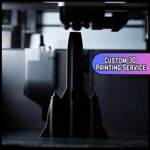 Puede incluir: Un modelo negro impreso en 3D de una estructura está siendo creado por una impresora 3D. La imagen muestra el cabezal de la impresora en acción, con el texto "CUSTOM 3D PRINTING SERVICE" en una pancarta morada y azul.