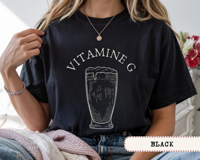 May include: Black t-shirt with the text "VITAMINE G" above a detailed illustration of a beer glass. The shirt features a vintage-style design, with the word "BLACK" at the bottom.