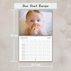 Może przedstawiać: Kalendarz ścienny o wymiarach 42 cm na 29,7 cm, oznaczony jako Size Chart Europe. G&oacute;rna część zawiera zdjęcie niemowlęcia trzymającego mały drewniany klocek. Dolna część przedstawia siatkę kalendarza na styczeń 2027 roku z czarnym tekstem na białym tle.