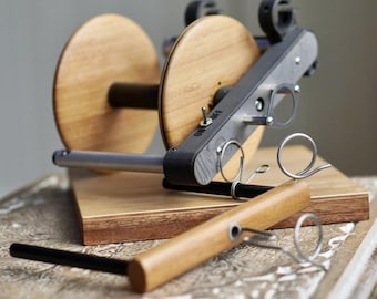 May include: A wooden spinning wheel with a metal frame and a wooden base. The wheel has two spools and a crank. The base has a small wooden handle. The wheel is labeled "ON OFF".