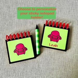 May include: Two personalized sticky notepad holders with red spiral binding, black borders, and lime green pages. Each notepad features a pink armchair graphic and the name "Leah" on one. A green and white striped crayon is also present. Text reads: "Choose to personalize your sticky notepad holder!"