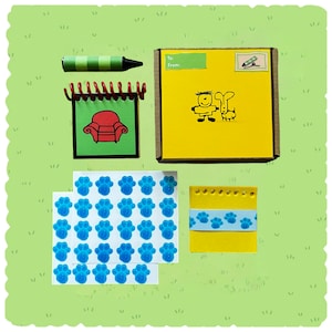 May include: A collection of themed stationery items, including a yellow box with a cartoon drawing, a green crayon, a notepad with a red chair illustration, paw print stickers, and a yellow notepad with a paw print ribbon.