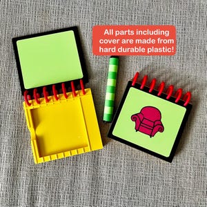 May include: A set of children's toys featuring a yellow notebook, a green and white striped crayon, and two notebooks with red spiral binding. One notebook has a green page and the other has a red armchair graphic. Text on the image reads: All parts including cover are made from hard durable plastic!