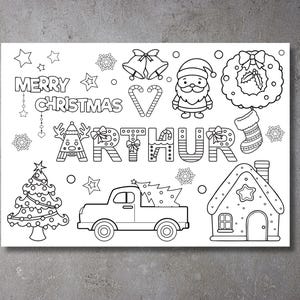 May include: A black and white colouring page featuring a Christmas scene with a truck, a gingerbread house, a Christmas tree, a wreath, a stocking, a Father Christmas, and the name "Arthur". The text "Merry Christmas" is also included.