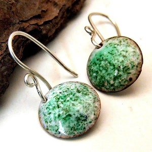 May include: A pair of silver dangle earrings with green and white speckled round ceramic charms.