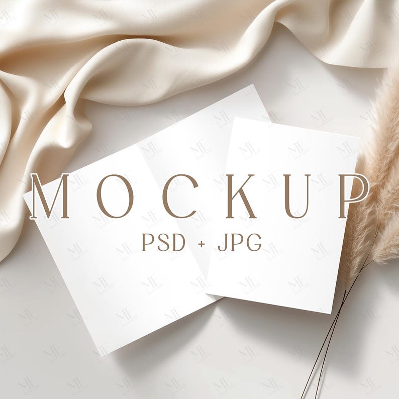 May include: A mockup scene featuring two white folded cards with the word "MOCKUP" in brown letters. The cards are on a white surface with a beige fabric and dried grass. The text "PSD + JPG" is below the word "MOCKUP".