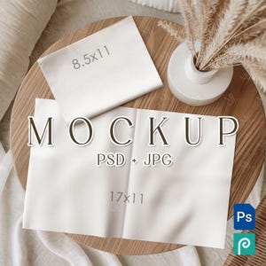 May include: A mockup scene with two white paper sheets, one measuring 8.5x11 inches and the other 17x11 inches, with the word "MOCKUP" in large letters. A small white vase with dried plants sits on a wooden surface.
