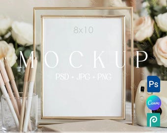 May include: A gold-framed 8x10 inch mockup with the word "MOCKUP" in white. The image includes pens in a glass, a small camera, and the text "PSD + JPG + PNG". The bottom of the frame has the text "EDITABLE IN PHOTOSHOP | PHOTOPEA | CANVA".