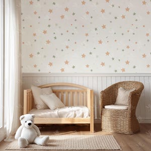 May include: A nursery scene with a light wood crib, a wicker chair, and a large white teddy bear. The wall is decorated with a star pattern in muted colors. A neutral rug and white curtains complete the room.