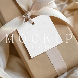 May include: A brown gift box with a white gift tag tied with a beige satin ribbon. The gift tag has the text "MOCKUP PSD + JPG" printed on it.