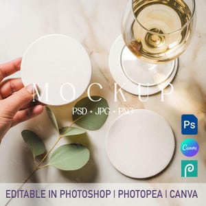 Pode incluir: Imagem de maquete com bases redondas brancas, uma taça de vinho branco e folhas de eucalipto. A palavra "MOCKUP" é exibida em uma fonte grande e elegante. A imagem também inclui texto indicando que é editável no Photoshop, Photopea e Canva.