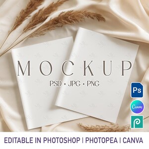 May include: Two white mockup books with the word "MOCKUP" printed on them. The text "PSD + JPG + PNG" is below the word "MOCKUP". The text "EDITABLE IN PHOTOSHOP | PHOTOPEA | CANVA" is at the bottom of the image.