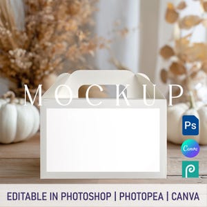 以下が含まれることがあります： 大きな大文字で「MOCKUP」と書かれたハンドル付きの白い箱。箱の前面には空白の白い長方形があります。「EDITABLE IN PHOTOSHOP | PHOTOPPEA | CANVA」というテキストが一番下にあります。