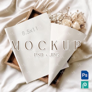 Puede incluir: Una hoja de papel blanca de 8,5 x 11 pulgadas y un cono de papel blanco con flores secas se muestran en una bandeja de madera. La bandeja está sobre un fondo de tela de color crema. El texto "MOCKUP PSD + JPG" está impreso en el papel.