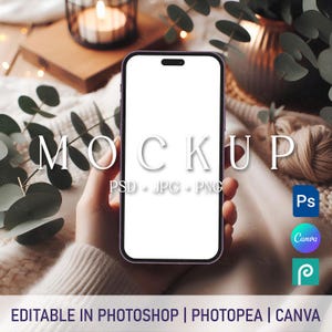 May include: A mockup of a smartphone with a white screen, held by a hand in a white sweater. The phone is surrounded by a cozy, wintery background with greenery and candles.