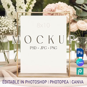 以下が含まれることがあります： 金色の金属フレームと、20 x 25 cmの白いモックアップ。 「MOCKUP」という単語は濃い茶色のフォントで表示されます。 モックアップは花と緑に囲まれています。 テキスト「PSD + JPG + PNG」は「MOCKUP」の下にあります。 テキスト「EDITABLE IN PHOTOSHOP | PHOTOPEA | CANVA」は一番下にあります。