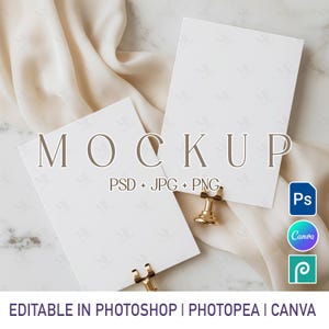 May include: A mockup image featuring two white rectangular cards with the word "MOCKUP" overlaid. The cards are held by gold-colored clips and rest on a draped fabric. Text includes "PSD + JPG + PNG" and "EDITABLE IN PHOTOSHOP | PHOTOPEA | CANVA".