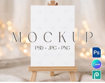 May include: A white rectangular mockup on a small wooden easel. The word "MOCKUP" is displayed in large, gray letters. Below, it reads "PSD + JPG + PNG." Icons for Photoshop, Canva, and Photopea are visible. The text "EDITABLE IN PHOTOSHOP | PHOTOPEA | CANVA" is at the bottom.
