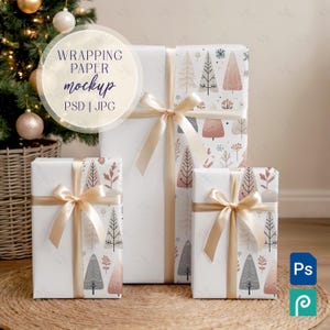 Könnte beinhalten: Drei verpackte Geschenke mit goldenen Schleifen. Das Geschenkpapier zeigt ein sich wiederholendes Muster aus stilisierten Bäumen in Grau-, Rosa- und Weißtönen. Die Geschenke sind auf einer gewebten Matte angeordnet, mit einem Weihnachtsbaum und Ornamenten im Hintergrund.