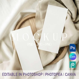 May include: Two blank white rectangular cards on a wooden embroidery hoop, draped over a beige fabric. The word "MOCKUP" is printed in white. The text "PSD JPG PNG" is below the word "MOCKUP". The text "EDITABLE IN PHOTOSHOP | PHOTPEA | CANVA" is at the bottom.