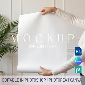 以下が含まれることがあります： 大きな文字で「MOCKUP」という言葉が書かれた、人が持っている白いモックアップポスター。ポスターには「PSD + JPG + PNG」という文字と、Photoshop、Canva、Photopeaのアイコンが含まれています。ポスターの下部には「EDITABLE IN PHOTOSHOP | PHOTOPEA | CANVA」と書かれています。