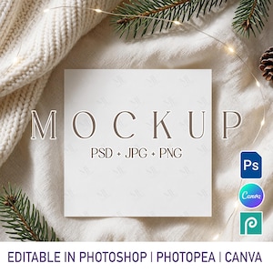 May include: A square white card mockup featuring the text MOCKUP PSD + JPG + PNG in brown lettering. The card is displayed against a textured white fabric background with pine branches and a string of small lights, including Photoshop and Canva icons.