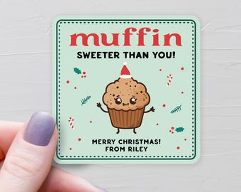 May include: A square sticker with a light green background and a dotted border. The sticker features a cartoon muffin wearing a Santa hat, with the text "muffin sweeter than you!" and "Merry Christmas! From Riley."