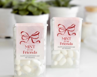 May include: Two clear plastic containers filled with white mints. Each container has a pink label with a red bow and the text "MINT TO BE Friends" and "Happy Galentine's Day XO AMANDA".