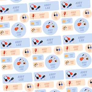 May include: Sheet of personalized labels with the name "ABBY LEE" in a playful font. The labels feature musical elements like headphones, microphones, guitars, and cassette tapes in a light blue and orange color scheme.