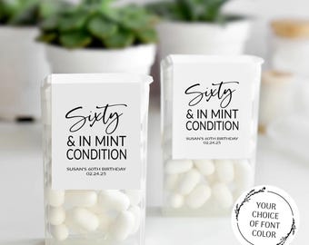 Peut inclure: Deux boîtes en plastique transparent remplies de menthes blanches. Chaque boîte porte une étiquette blanche avec le texte "Sixty & IN MINT CONDITION" et "SUSAN'S 60TH BIRTHDAY 02.24.25" en écriture noire. Un graphique circulaire indique "YOUR CHOICE OF FONT COLOR".