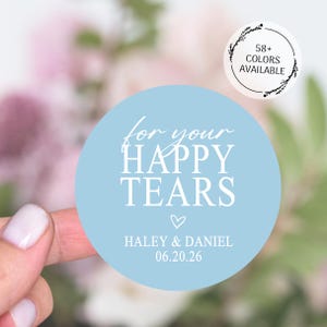 Peut inclure: Un autocollant rond bleu clair avec le texte "for your HAPPY TEARS" en blanc. En dessous, un petit cœur et les noms "Haley & Daniel" avec la date "06.20.26". Un petit autocollant indique "58+ COLORS AVAILABLE".