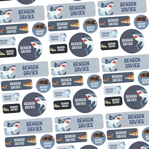 May include: A sheet of personalized name labels featuring the name "BENSON DAVIES". The labels are in various shapes, including rectangles and circles, and feature shark and fish illustrations in shades of blue, gray, and brown.