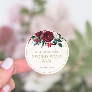 May include: Round white sticker with a red and green floral design. The text reads "Homemade by Emily Spiced Pear Jam Christmas 2024".