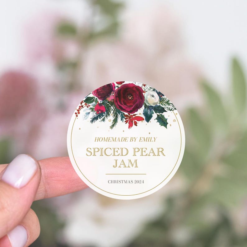 May include: Round white sticker with a red and green floral design. The text reads "Homemade by Emily Spiced Pear Jam Christmas 2024".