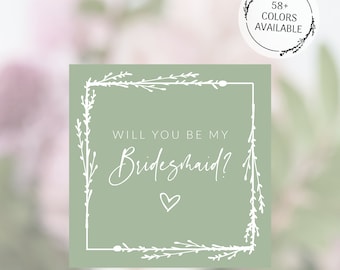 Puede incluir: Una tarjeta verde con un borde floral blanco y el texto "¿Quieres ser mi dama de honor?" con un pequeño corazón en el centro. La tarjeta está disponible en 58 colores.