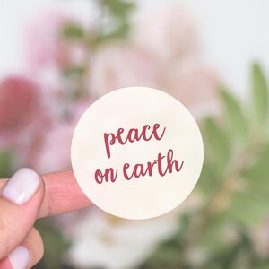 May include: A white round sticker with the words "peace on earth" written in red cursive.