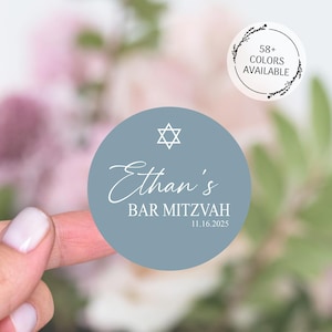 May include: A light blue round sticker with a white Star of David, the text "Ethan's Bar Mitzvah 11.16.2025" and a white cursive font.