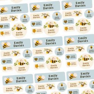 May include: A collection of personalised name labels with the name "Emily Davies". The labels feature bee illustrations, honey pots, and floral designs. The colour scheme includes yellow, black, and light blue, suitable for children's items.