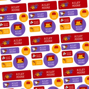 May include: A pattern of stickers with a theater theme. The stickers feature the name "Riley Moore" in white text on red, purple, and yellow backgrounds. Designs include theater masks, stage curtains, and bouquets.