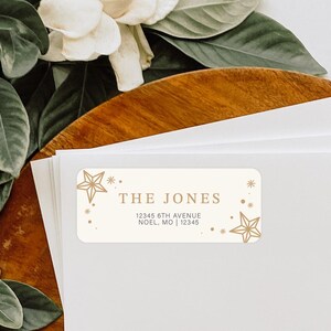 May include: A white return address label with gold stars and a gold outline. The text on the label reads "THE JONES 12345 6TH AVENUE NOEL, MO | 12345".