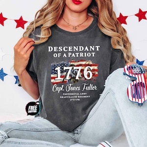 May include: A charcoal gray short-sleeve t-shirt featuring the white text DESCENDANT OF A PATRIOT, 1776, and Capt. Jones Fuller, Continental Army, Granville NC Regiment, 1771-1781. A graphic of an American flag is centered behind the number 1776.