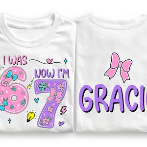May include: Two white t-shirts featuring colorful graphic designs. The left shirt displays the text I WAS NOW I'M with a pink number 6 and a purple number 7 decorated with flowers, bows, and stars. The right shirt features a pink bow and the name GRACIE in large purple letters.