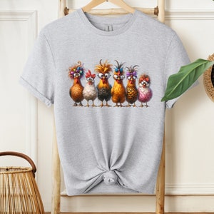 May include: A gray t-shirt with a graphic of six chickens wearing colorful accessories. The chickens are lined up in a row and have different expressions on their faces.