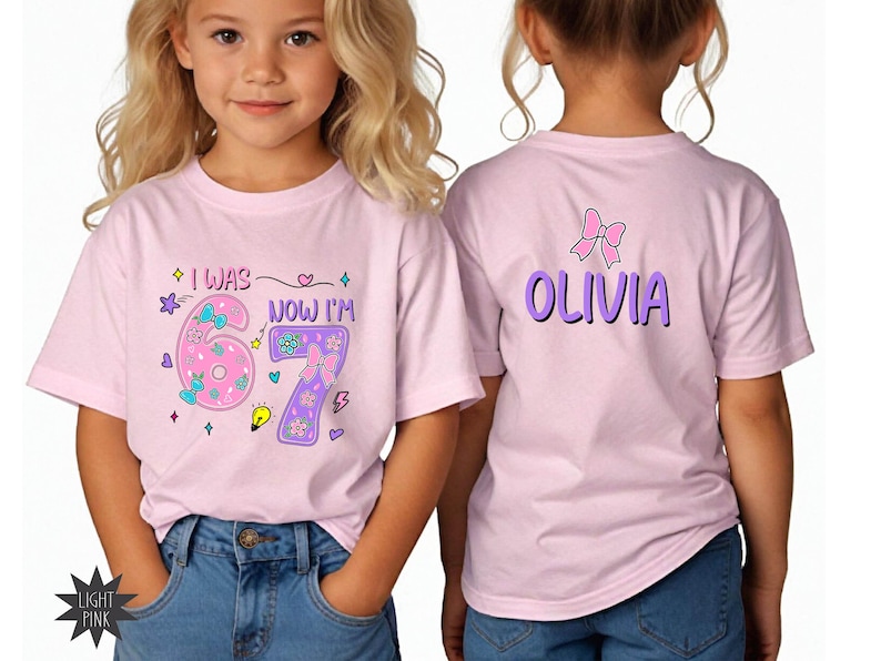 May include: A light pink t-shirt featuring a graphic on the front that reads I WAS 6 NOW I'M 7 with colorful flowers, bows, and stars. The back of the shirt displays the name OLIVIA in purple letters with a pink bow graphic positioned above the name.