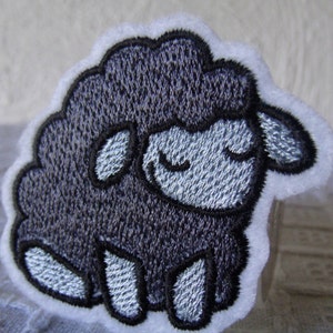 May include: A black embroidered sheep with a white background. The sheep has a closed-eye expression and is sitting on its hind legs.