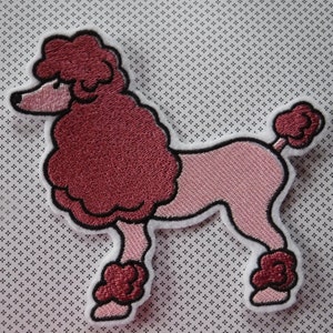 May include: Pink and red embroidered poodle patch. The poodle is standing on all four legs with its tail curled up. The patch is perfect for adding a touch of whimsy to clothing, bags, or other accessories.
