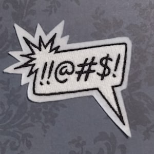 May include: White embroidered patch with a black outline in the shape of a speech bubble with a starburst behind it. The speech bubble says "!@#$!".