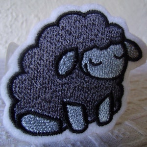 May include: A gray embroidered patch of a sheep with a closed eye expression.
