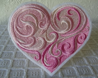 May include: A pink and white embroidered heart-shaped patch with a swirling design.